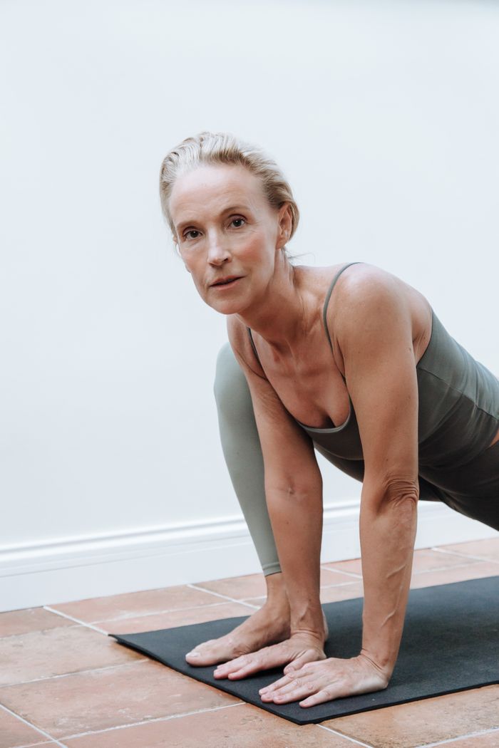 gallery-1 Senior woman in sportswear performing yoga on a mat indoors, demonstrating fitness and health.