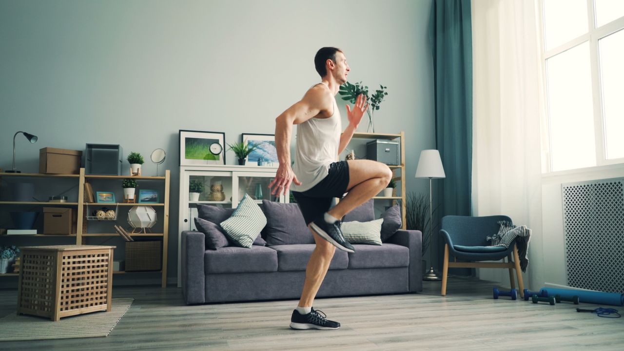 gallery-3 A man in sportswear exercising indoors with a modern living room background.