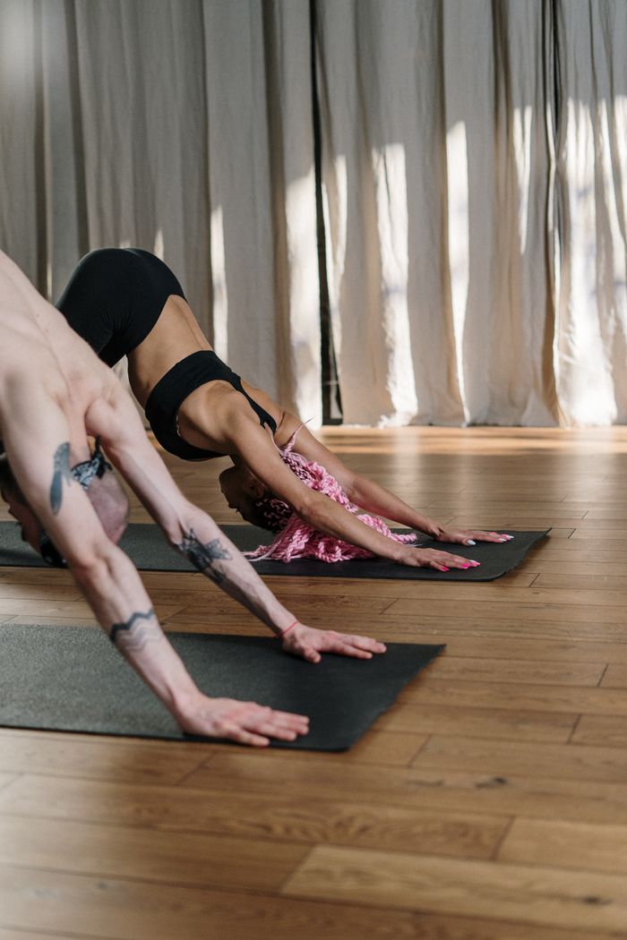 services-01 Two people practicing yoga indoors showcasing flexibility and fitness.