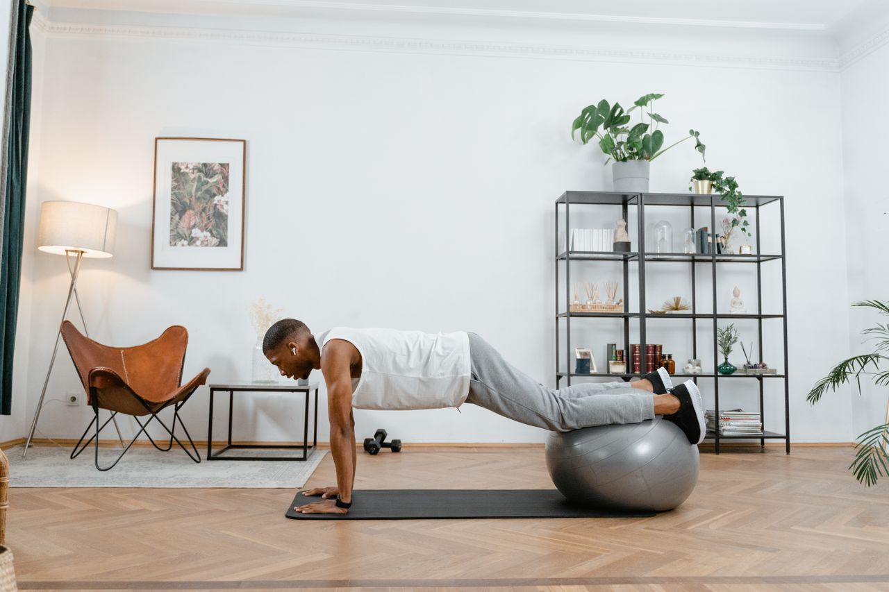 gallery-4 Adult man working out with stability ball indoors, promoting a healthy lifestyle.