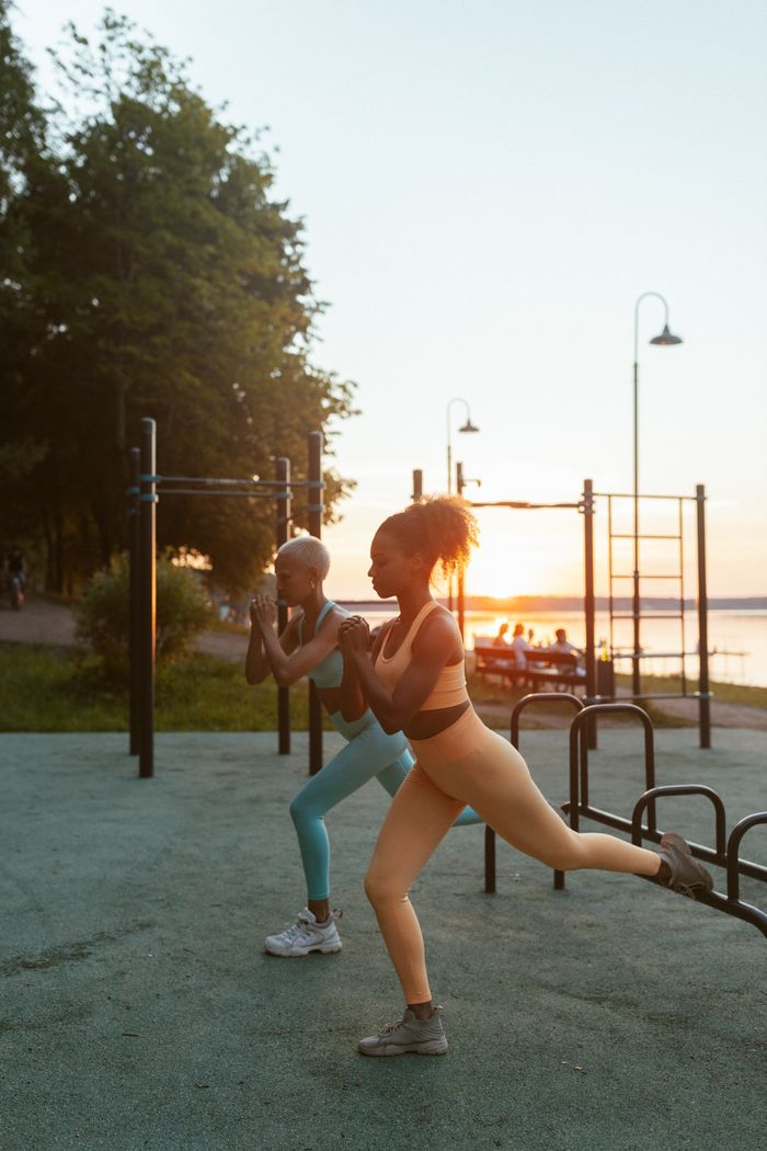 contact-img Two women exercising outdoors at sunset, demonstrating fitness and health.